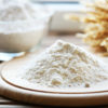 Pile of flour on cutting board with glass bowl, closeup