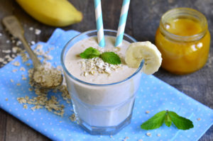 Banana smoothie with honey and oats on a wooden table.