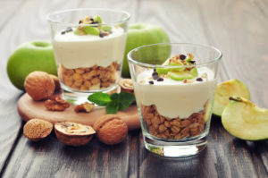 Homemade dessert with apple, nuts, yogurt and granola in glasses
